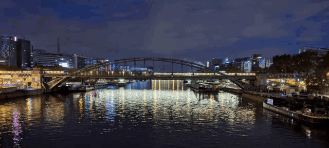 a bridge over a body of water at night with buildings in the background