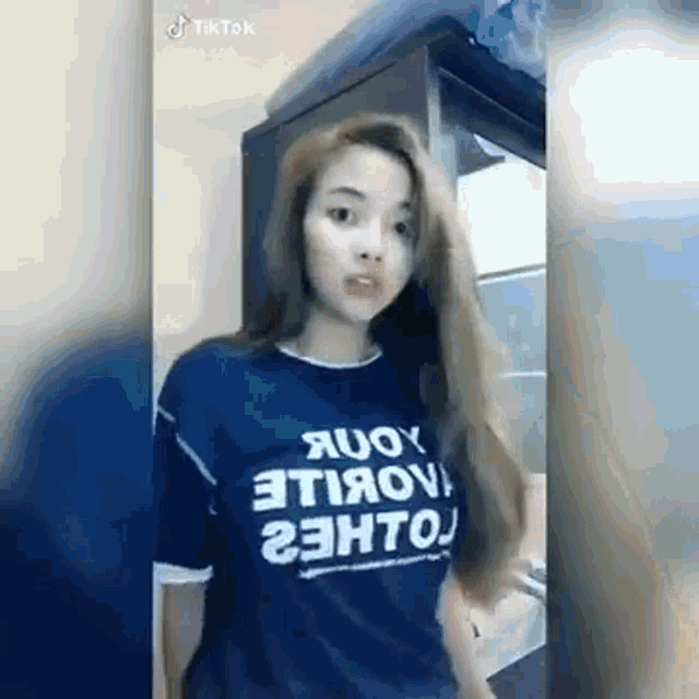 a woman in a blue t-shirt is standing in front of a door .
