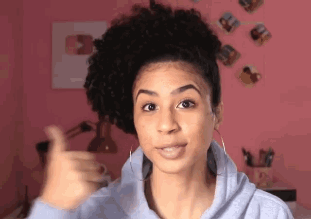 a woman giving a thumbs up with a pink background
