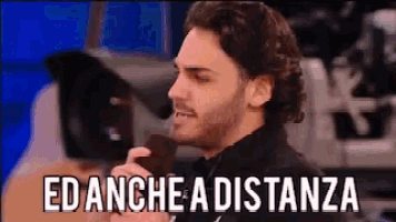 a man in a suit is talking into a microphone with the words " edanche a distanza " written below him