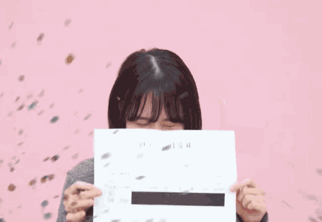 a girl in a gray sweater is holding a white box in her hands .