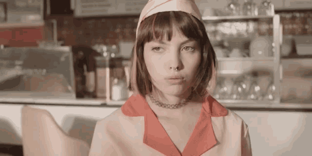 a woman in a pink and red diner uniform is sitting at a table .
