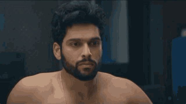 a shirtless man with a beard is standing in front of a mirror .