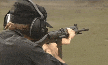 a man wearing ear muffs is holding a rifle