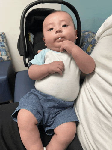 a baby is sitting in a car seat and making a funny face