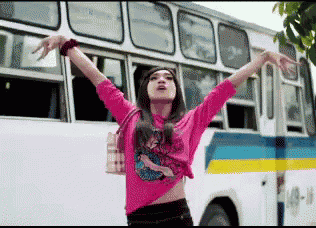 a woman in a pink shirt is standing in front of a bus with the number 4 on the side