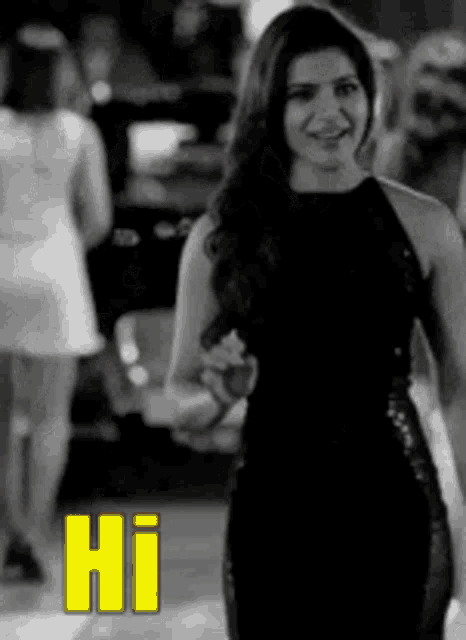 a woman in a black dress is standing in front of a crowd and says hi