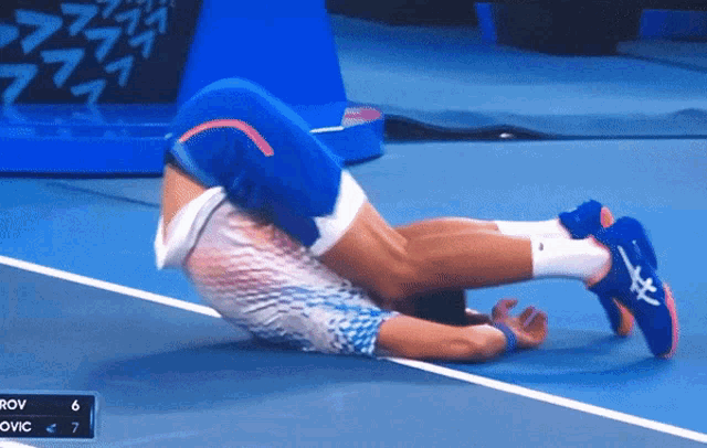 a man is laying on his back on a tennis court with a score of 6 to 7