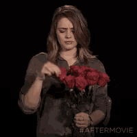 a woman holding a bouquet of red roses with #aftermovie on the bottom