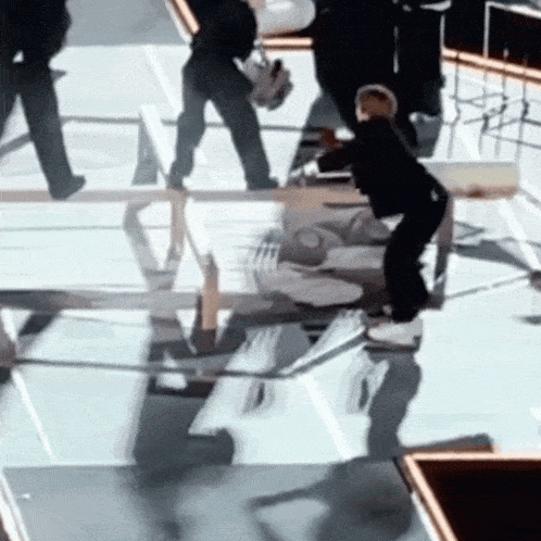 a group of people are standing around a table with a reflection of a person in the table