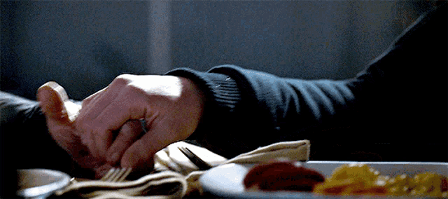 a close up of a person 's hand reaching for a fork