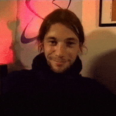 a man in a black turtleneck is smiling in front of a nike poster