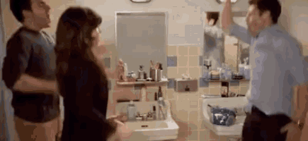 a group of people are standing in a bathroom with a sink and mirror .