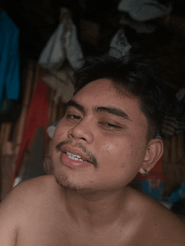 a shirtless man with a beard is smiling