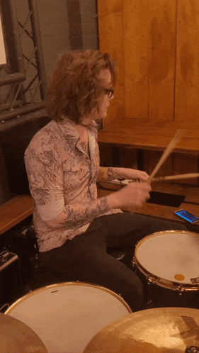 a man is playing a drum set with a phone on the floor