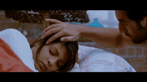 a man is touching a woman 's forehead in bed