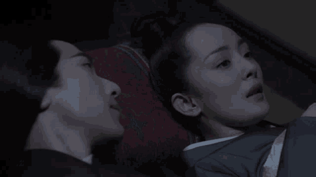 a man and a woman are laying next to each other on a bed in a dark room .