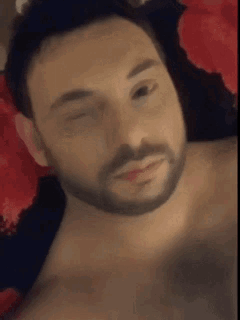 a man with a beard is laying on a bed with his eyes closed