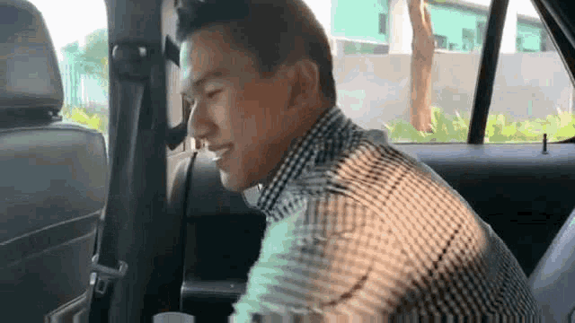 a man is sitting in the back seat of a car and smiling .