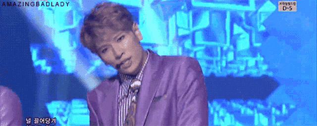 a man in a purple suit stands on a stage with the words amazingbadlady on the bottom right