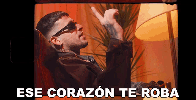 a man sitting in a chair with the words " ese corazon te roba " below him