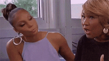 two women are sitting next to each other and talking .
