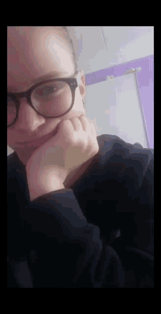 a girl wearing glasses and a black shirt is taking a selfie