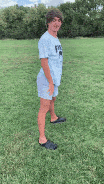 a young man wearing a blue shirt with the word fire on it is standing in the grass