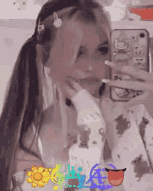 a girl is taking a selfie in front of a mirror with her tongue out .