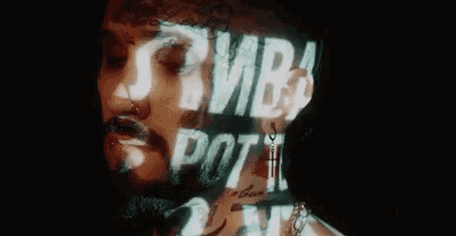 a close up of a man 's face with a beard and a tattoo .