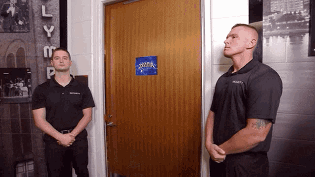 two men standing in front of a door that has a sign on it that says superhero