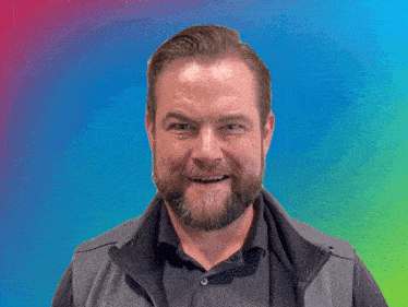 a man with a beard is making a funny face in front of a banner that says brilliant