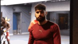 a man wearing a red puma shirt stands in a gym