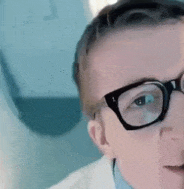 a close up of a person wearing glasses and a lab coat .