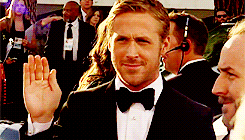 a man wearing a tuxedo and bow tie is waving his hand