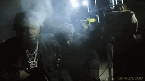 a gif from gifrun.com shows a man smoking a cigarette in the dark