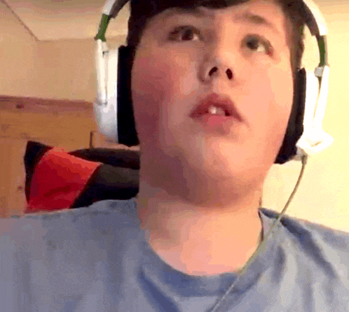 a young boy wearing headphones and a blue shirt looks at the camera