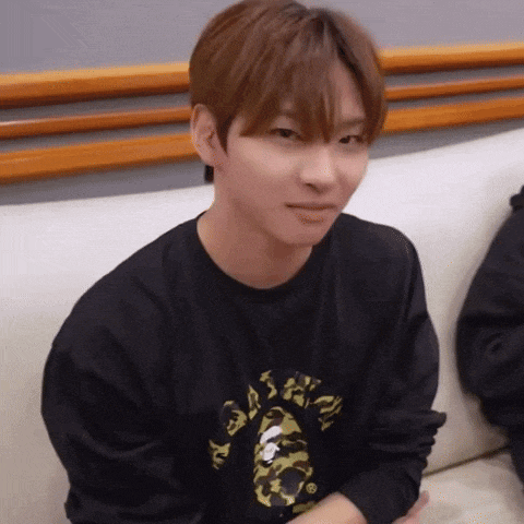 a young man is sitting on a couch wearing a black shirt with a camouflage print .