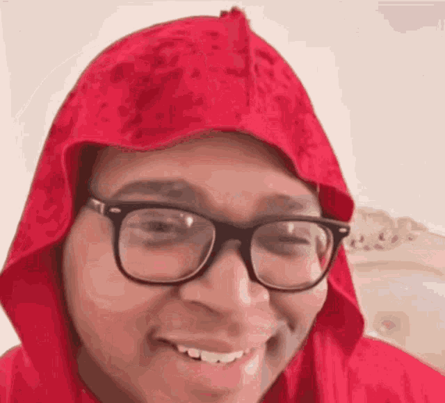 a man wearing glasses and a red hood is smiling for the camera