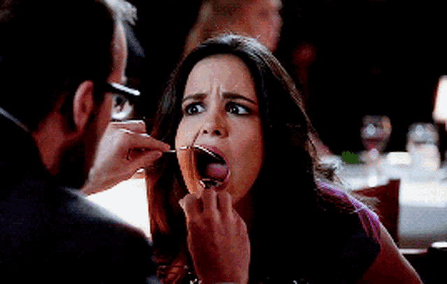 a man is feeding a woman a piece of food with a spoon