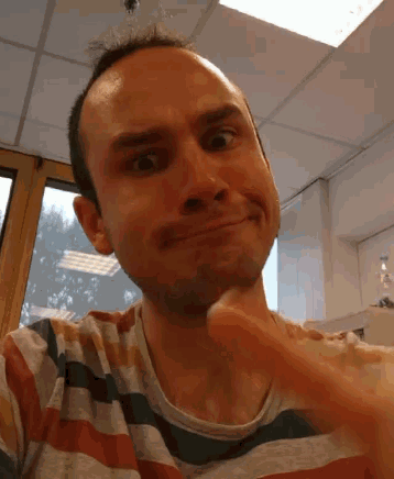 a man in a striped shirt is smiling and making a face