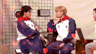 a man and a woman are sitting next to each other in a room with hearts on their shirts .