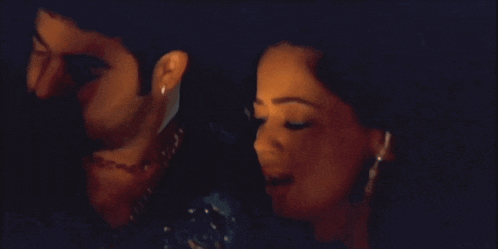 a man kisses a woman 's neck in a dark room