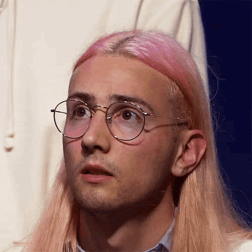 a man with long pink hair wearing glasses