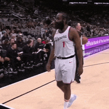 a basketball player with the number 1 on his jersey walks on the court