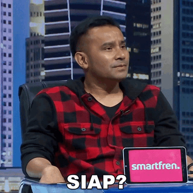 a man sitting at a table with a tablet that says smartfren