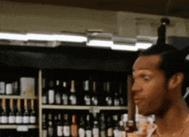 a man stands in front of a shelf of wine bottles with the number 99 on it