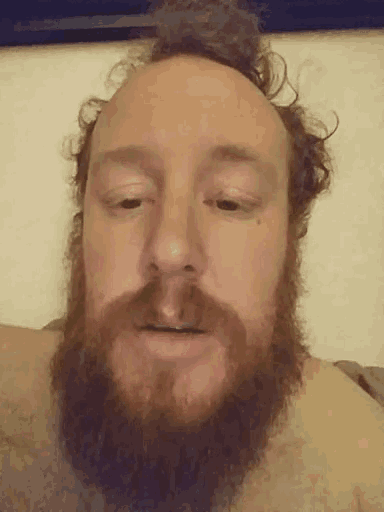 a man with a beard has his eyes closed and his mouth open .