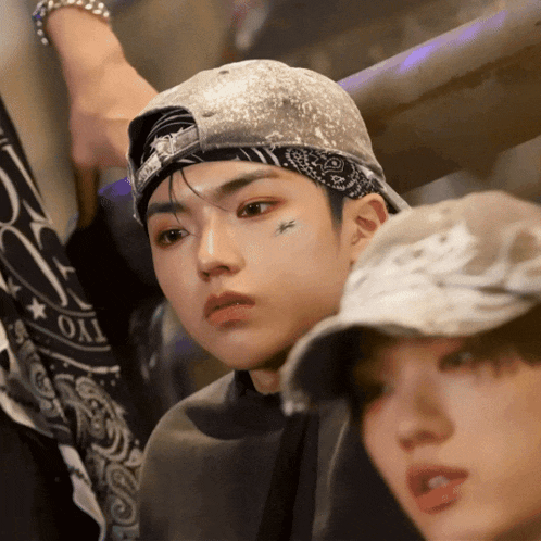 a man wearing a bandana and a baseball cap has a tattoo of a butterfly on his face