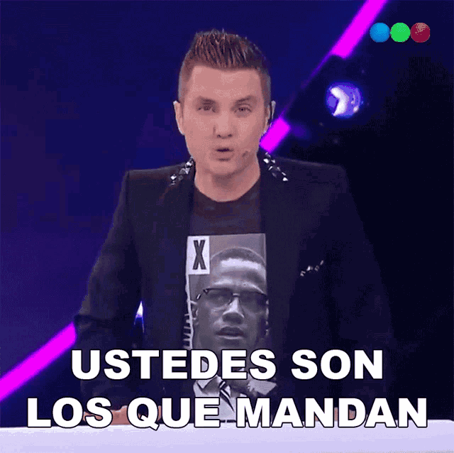 a man in a suit stands in front of a sign that says ustedes son los que mandan